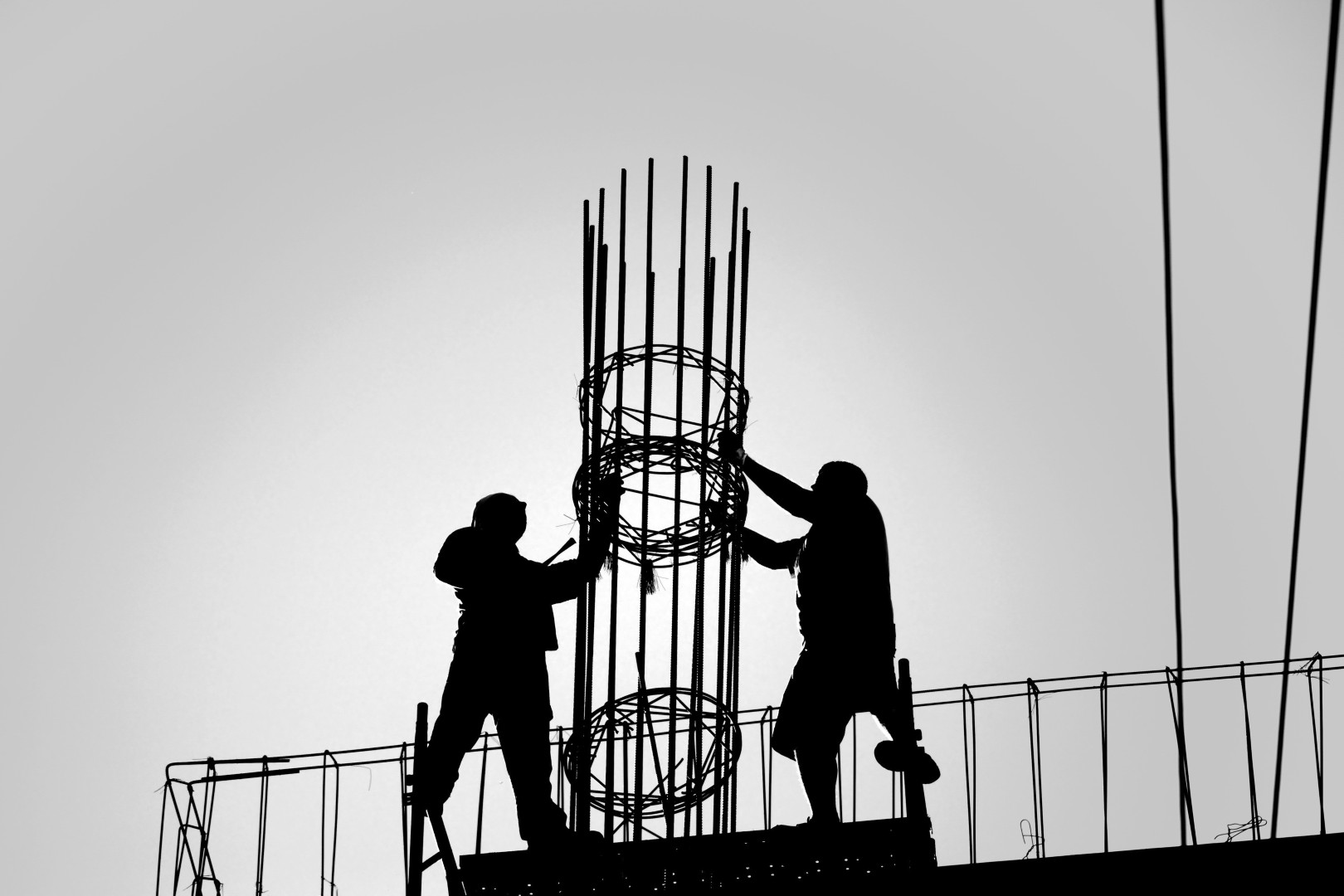 Two construction workers holding rebar for concrete structure